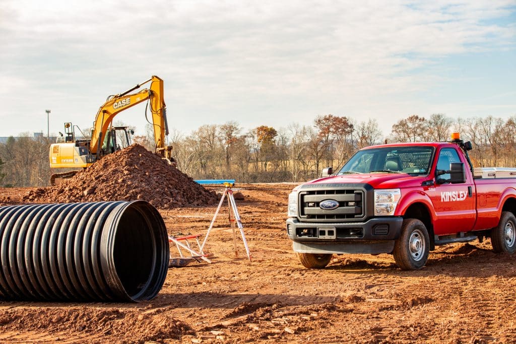 Red Kinsley truck and an excavator on an active job site