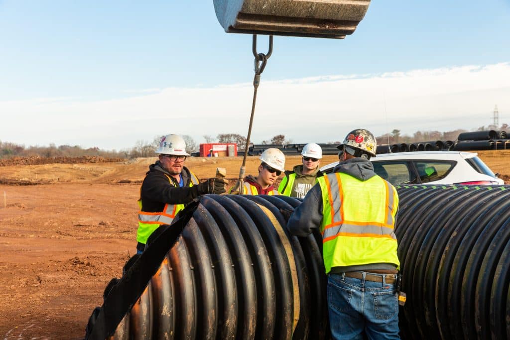 Construction crew of pipelayers getting ready to place pipe in the ground